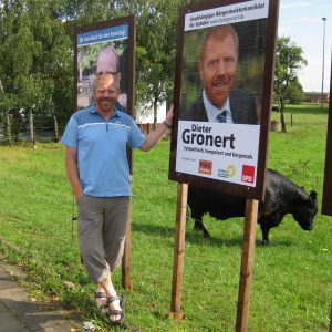 Dieter Gronert vor dem Plakat in Tonnenheide.